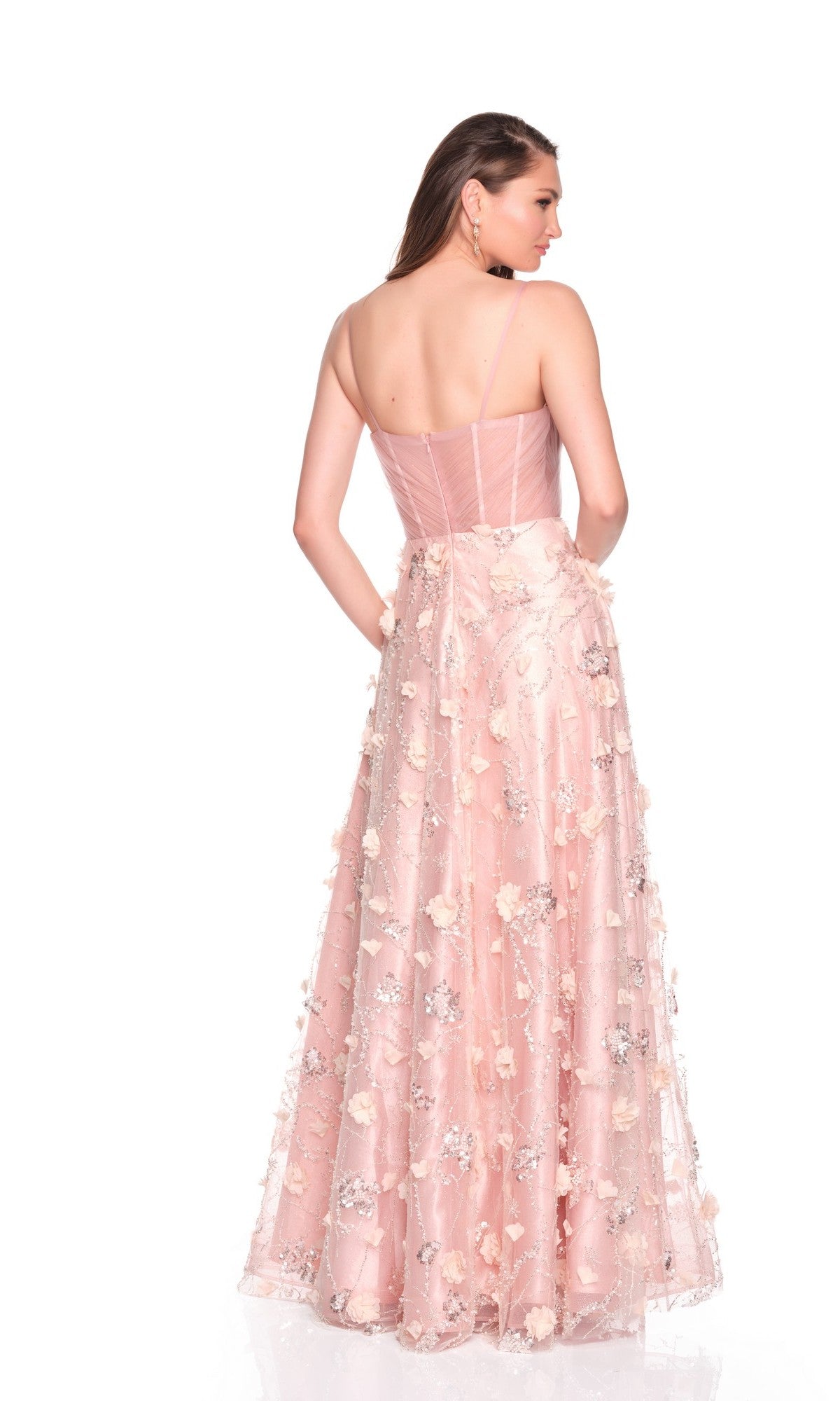 A woman faces away against a white background wearing the Dave and Johnny 12700 long prom dress, featuring light-pink fabric, 3D floral appliques, and a semi-sheer corset bodice.